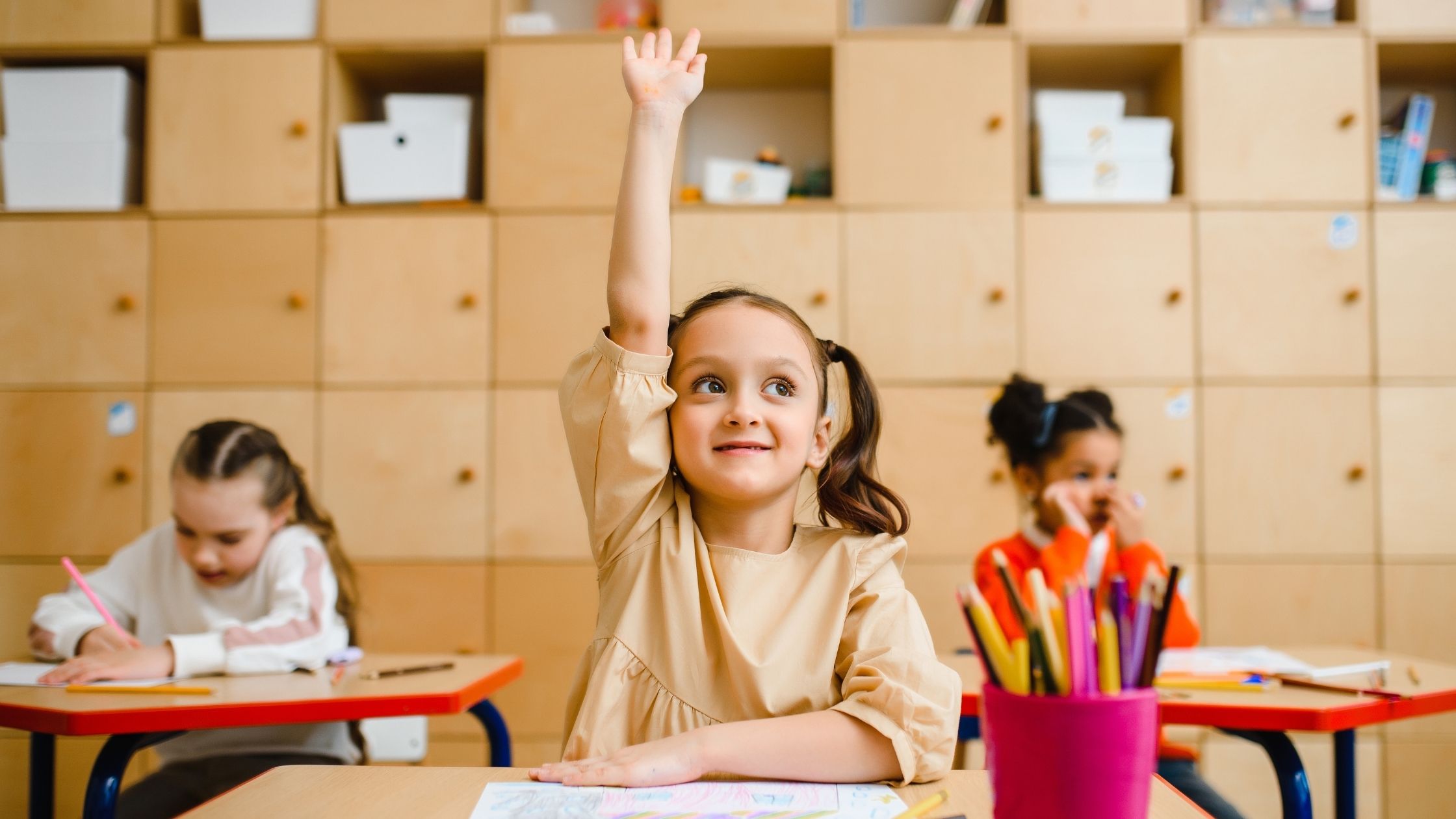 A small gril rasing hand in classroom